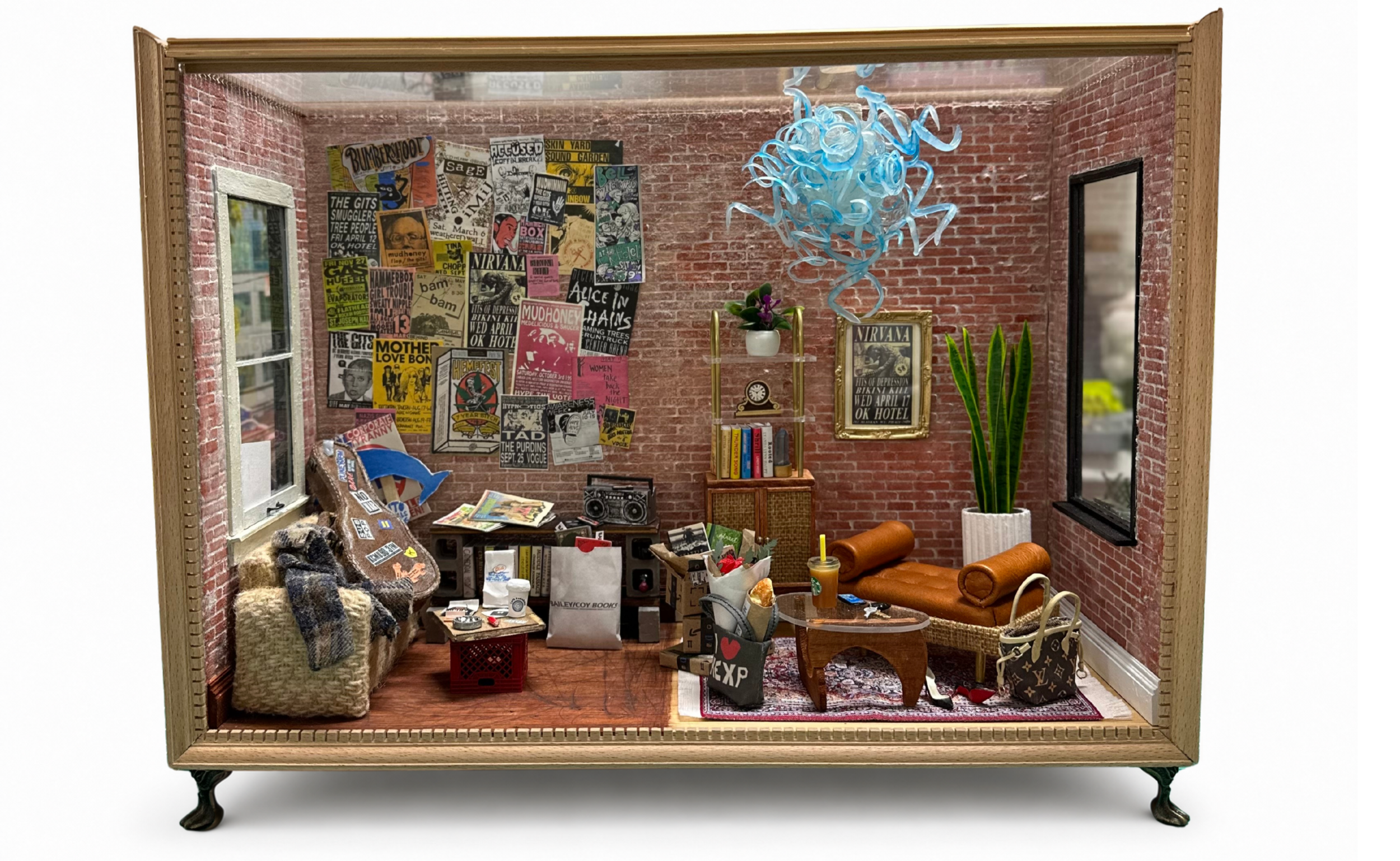 Miniature room with brick walls, decorated with posters, plants, and furniture, resembling a cozy apartment or studio.
