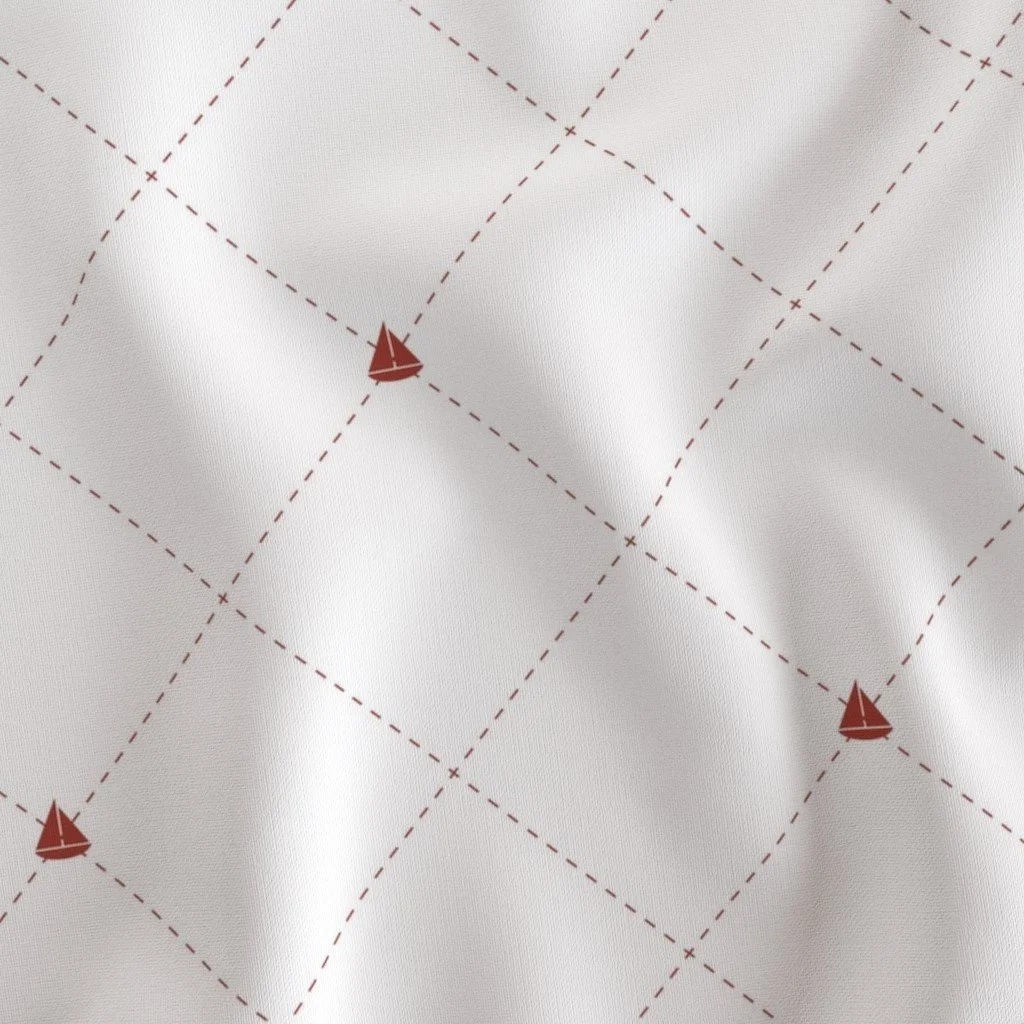 Close-up of a white fabric with a red diamond pattern and small red sailboat icons at some intersections.