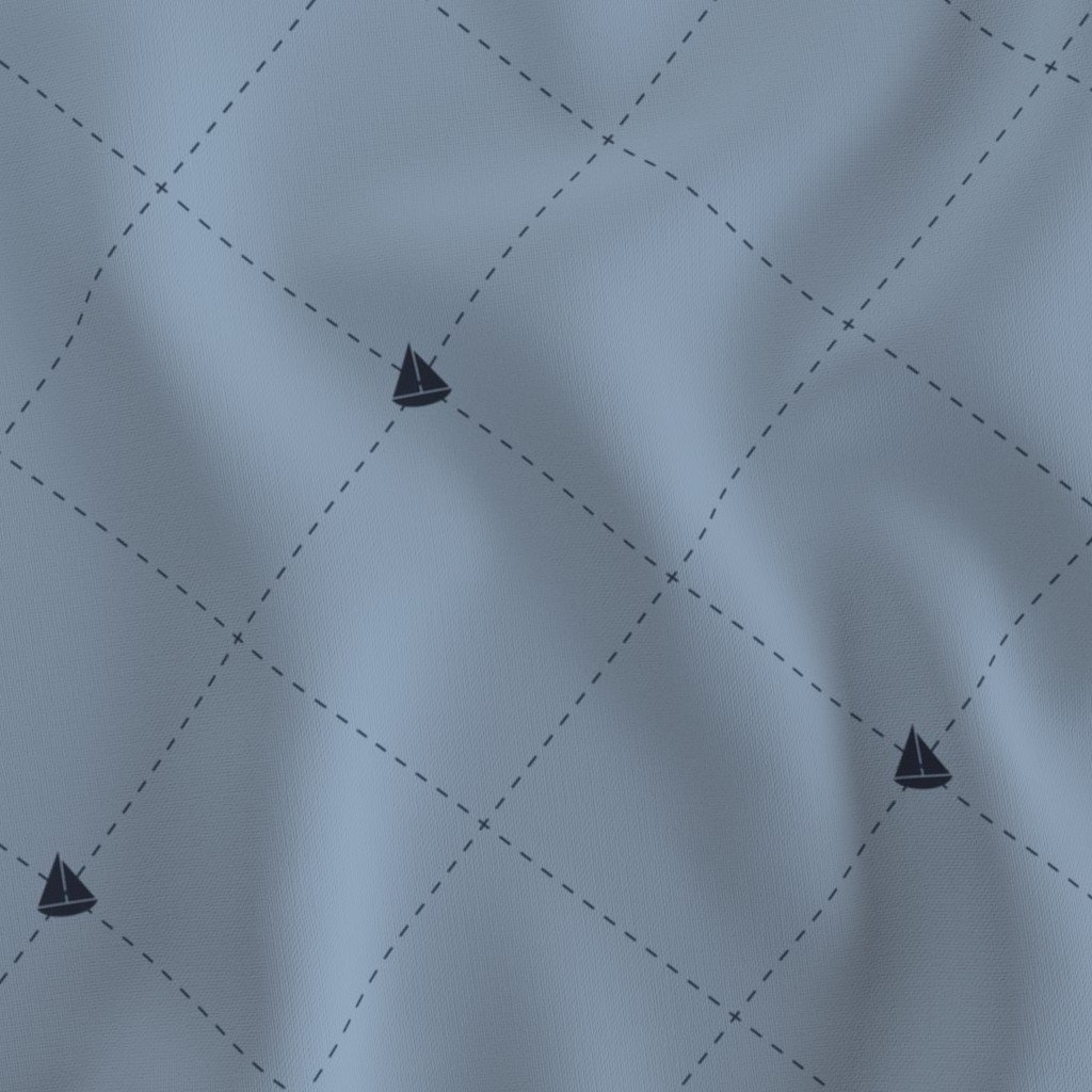 Close-up of light blue fabric with a nautical sailboat print and a quilted diamond pattern.