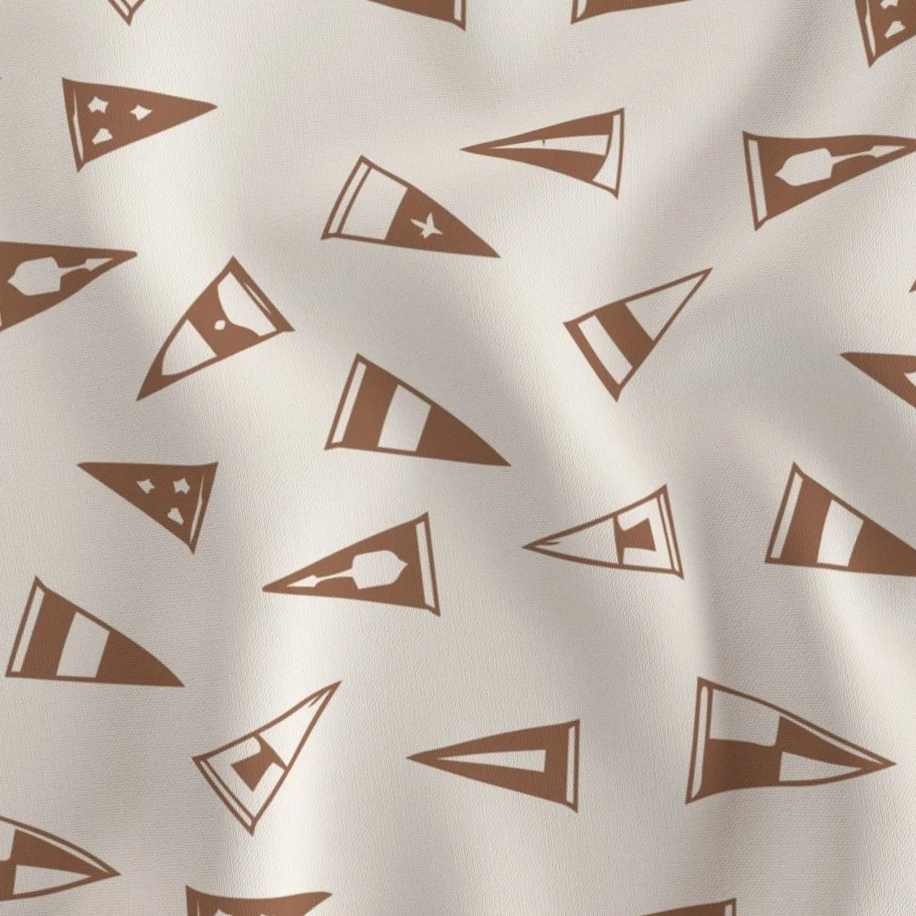 Pattern of small, brown, triangle-shaped party hats with various designs on a white fabric background.
