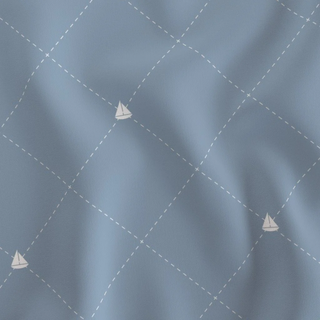 Close-up of light blue fabric with a sailboat pattern and dashed lines.