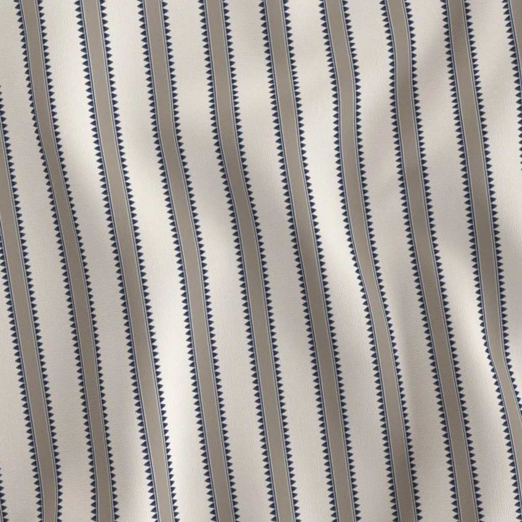 Close-up of striped fabric with beige, navy, and white colors and small geometric patterns.