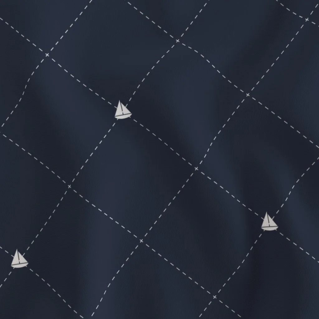 Close-up of dark fabric with a nautical pattern featuring white sailboats and dashed grid lines.