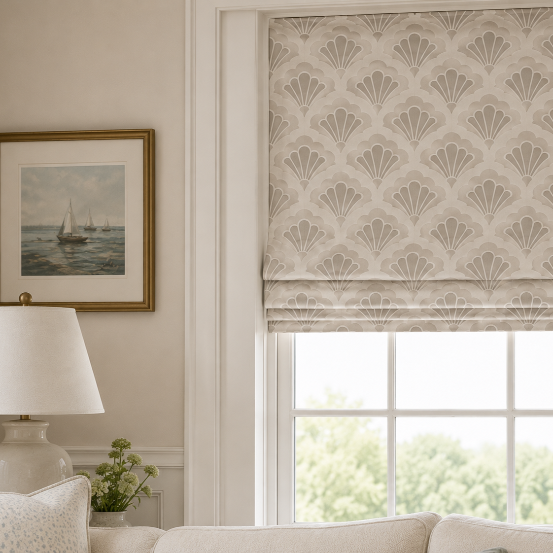 A window with a patterned Roman shade, a framed nautical painting on the wall, a white table lamp, and a small vase with green flowers.