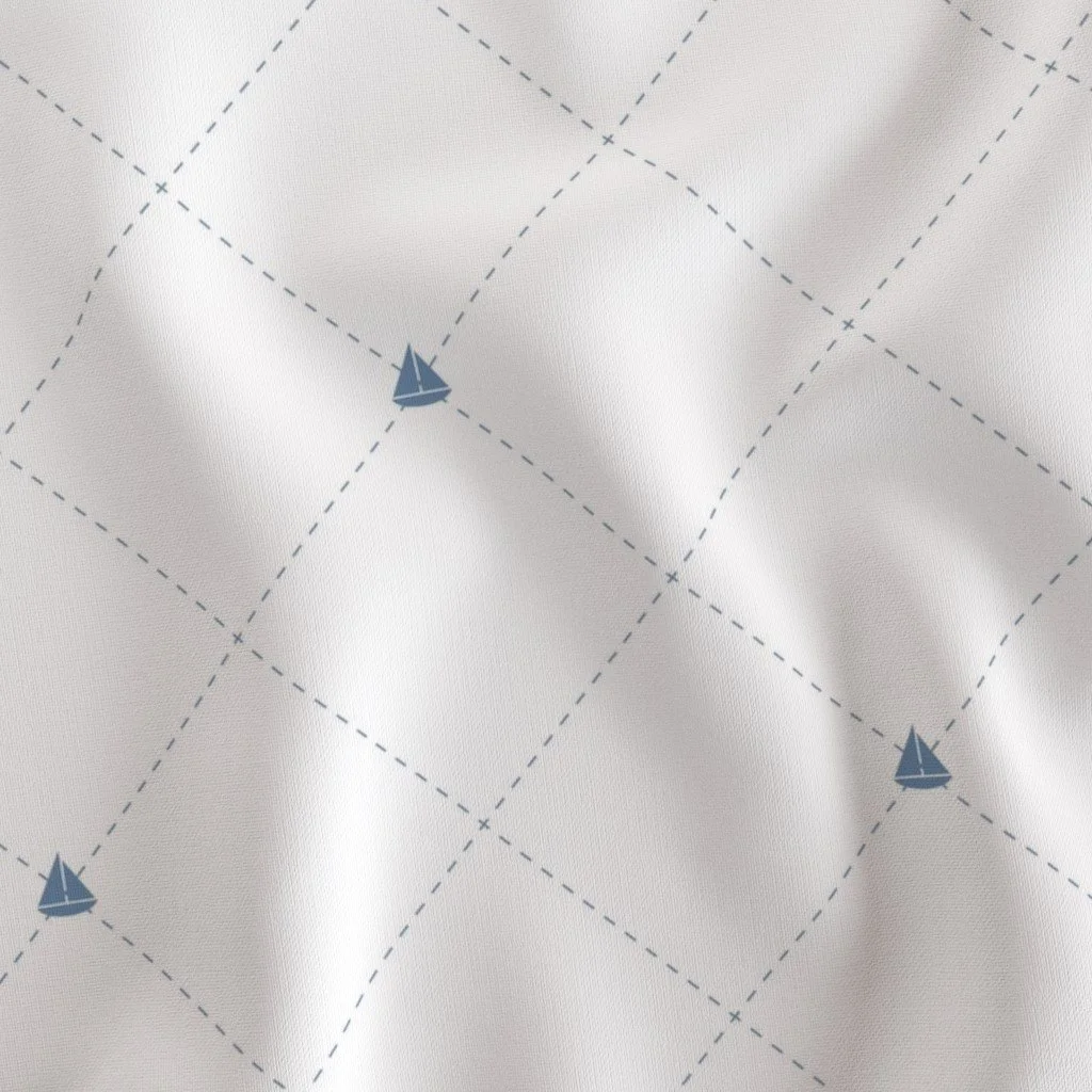 Close-up of white fabric with a blue sailboat pattern and a grid of dashed lines.