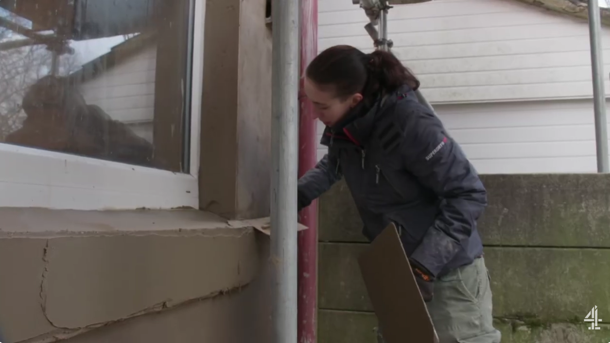 Naomi is rendring the outside of a house with a plastering trowel