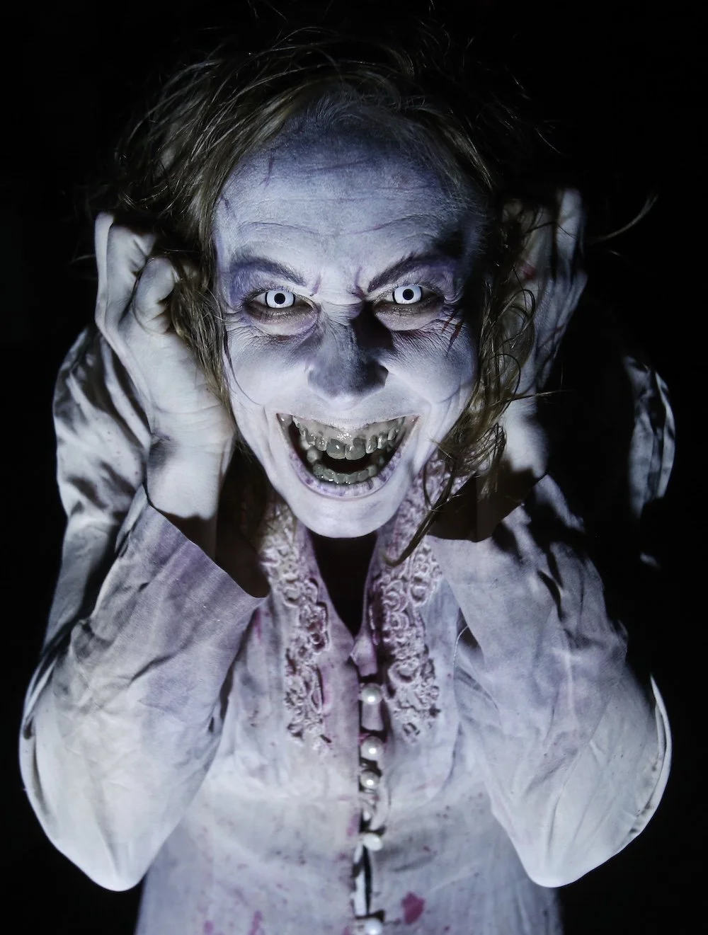 Demonic female creature with glowing eyes and sharp teeth at ScareHouse haunted attraction in Pittsburgh.