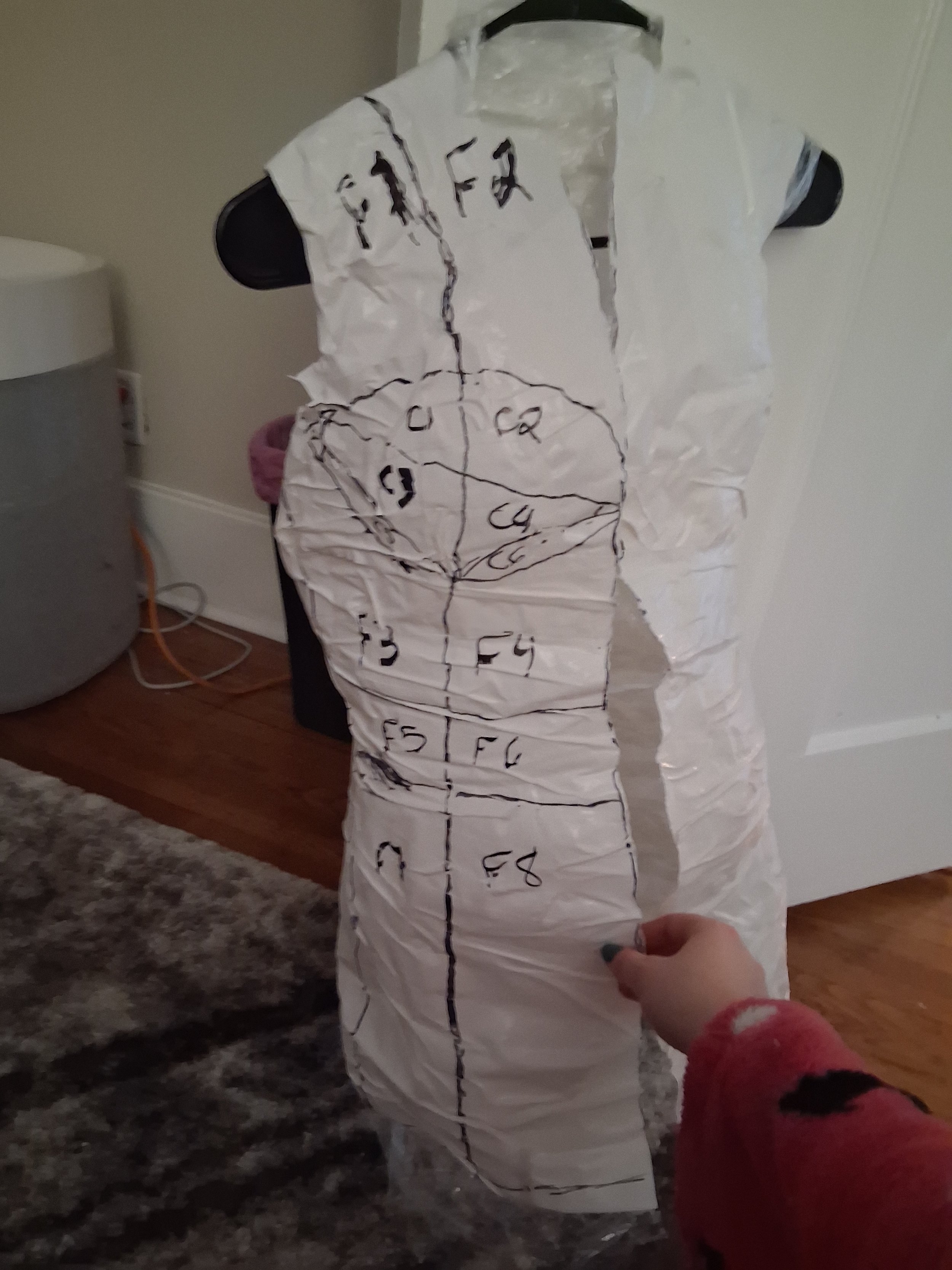 The beginning of a dress form I made from scratch. I plastic wrapped myself, then duct taped my torso, then drew on the guidelines, then cut the form off my body.