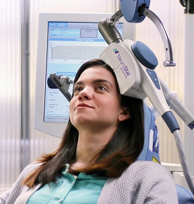 Woman undergoing a neurological brain scan with NeuroStar Transcranial Magnetic Stimulation device in a medical setting.