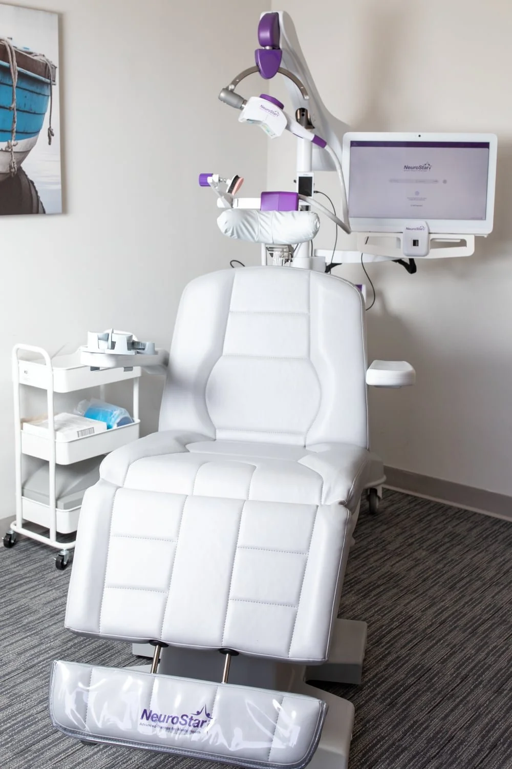 Medical examination chair in a clinic room with a monitor and medical equipment, labeled NeoStar.