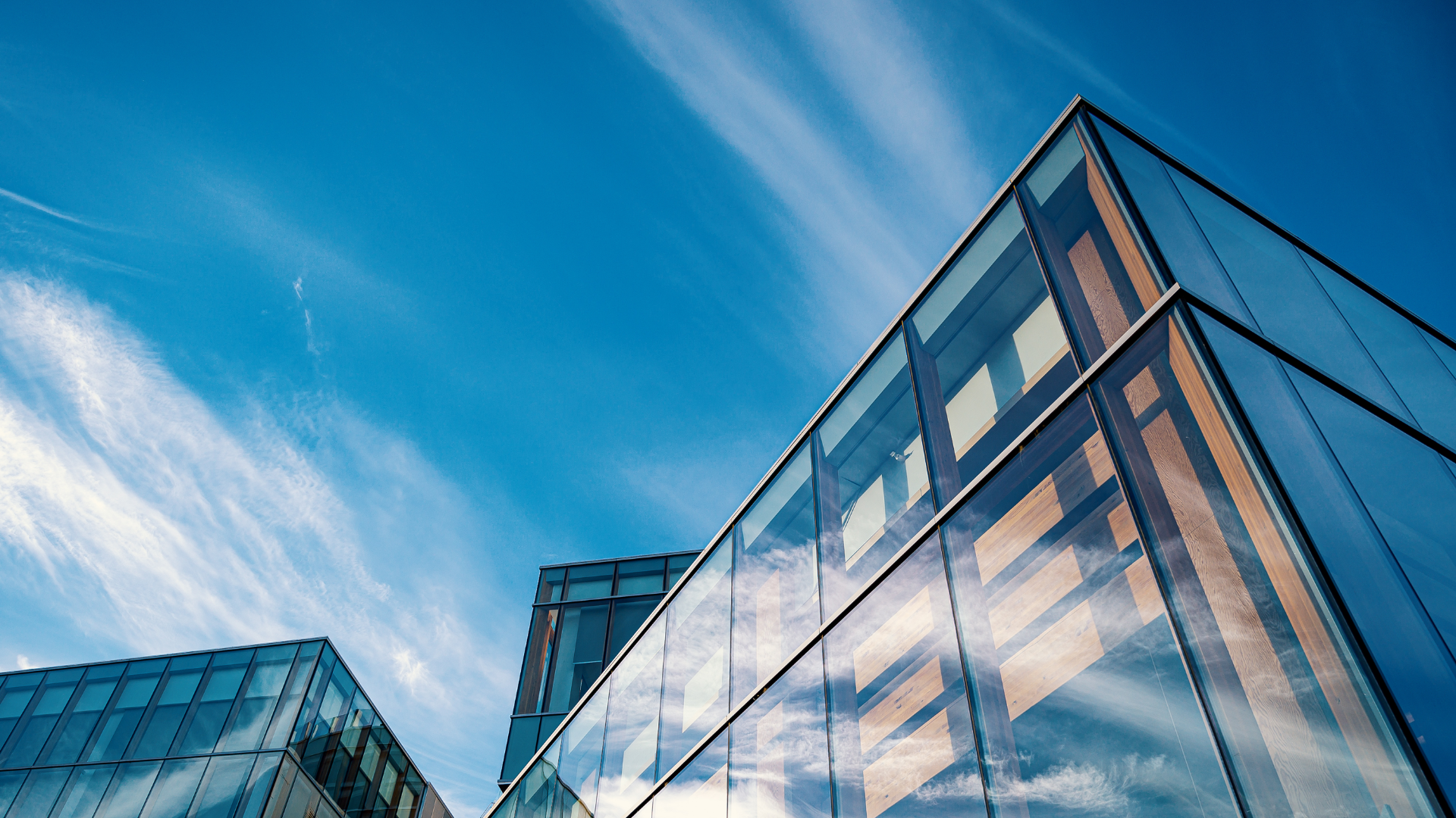 Modern glass office building reflecting the sky and clouds.
