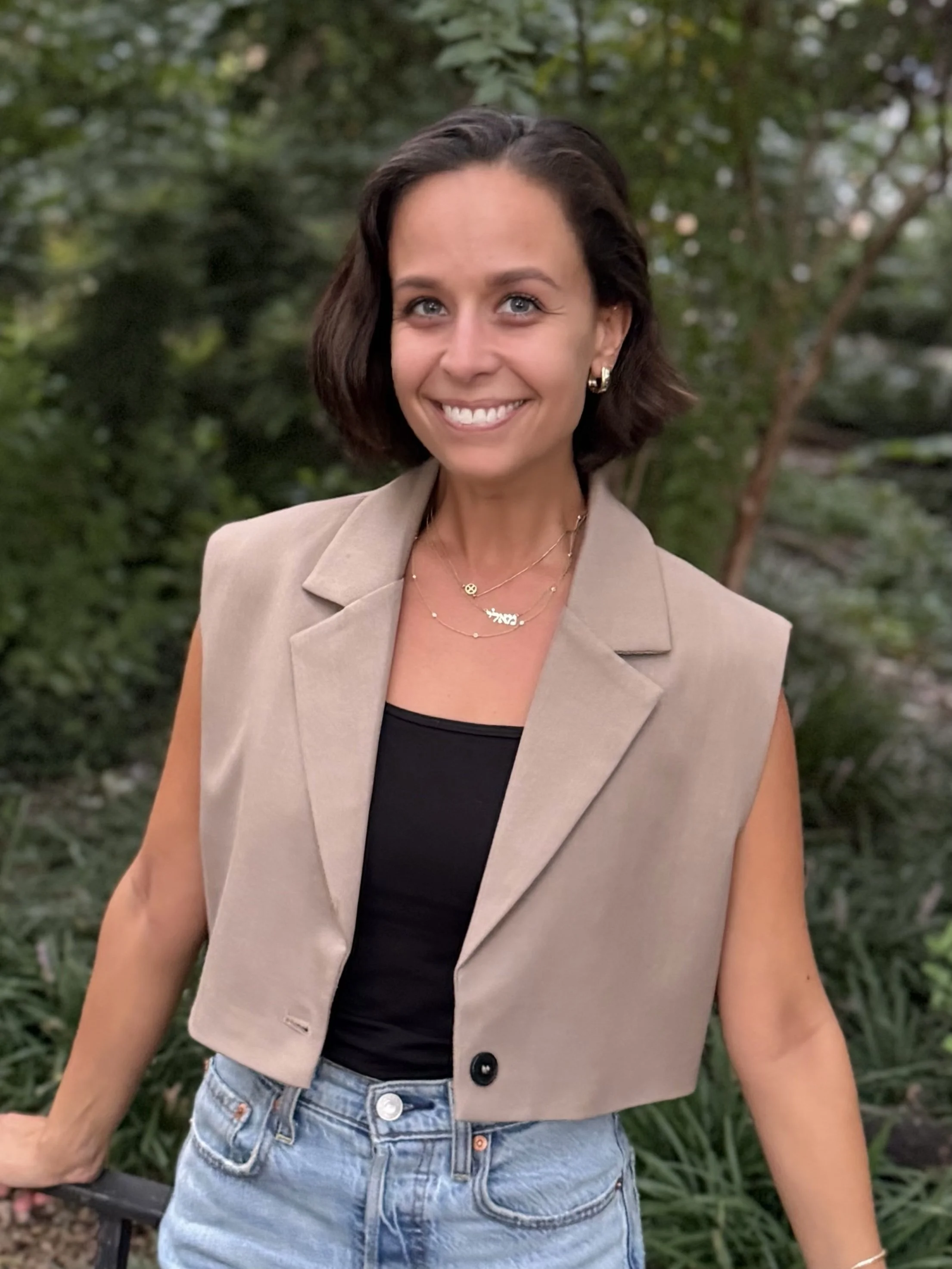 Smiling, kind therapist in front of green foliage in brooklyn