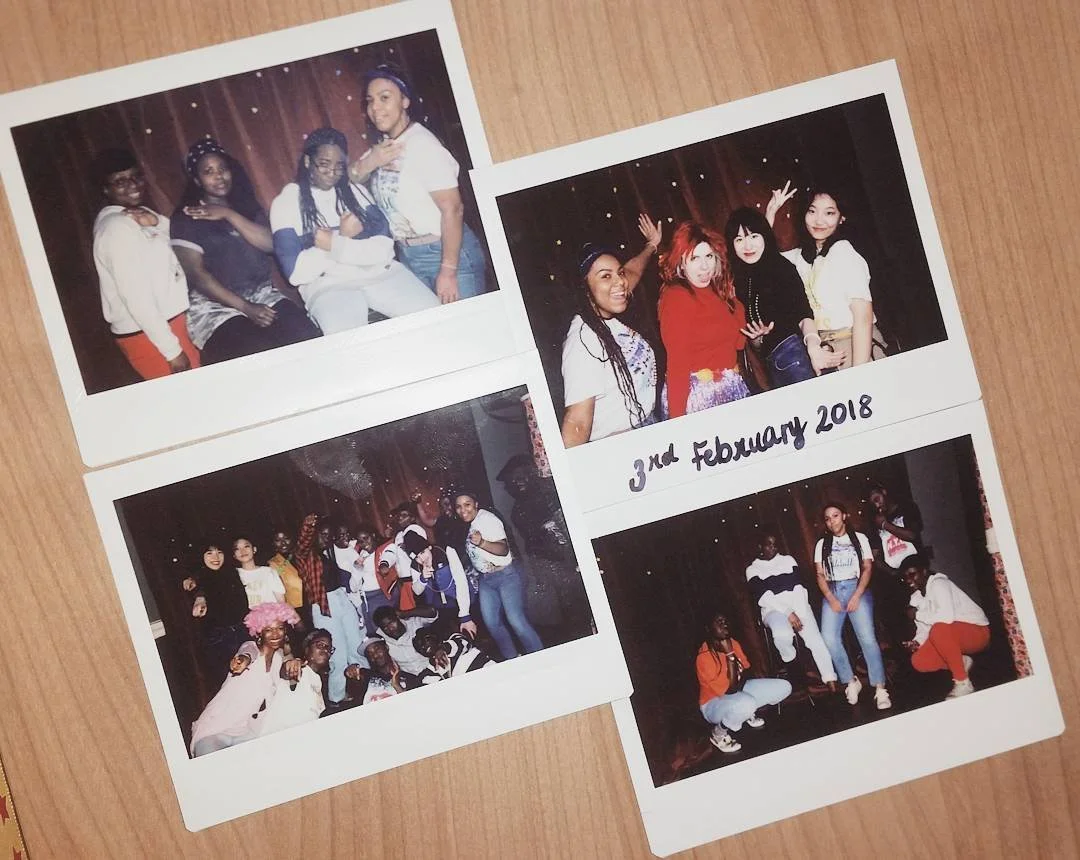 Four printed photos of groups of young women at a social event on wooden surface, one of which has '3rd February 2018' handwritten on it.