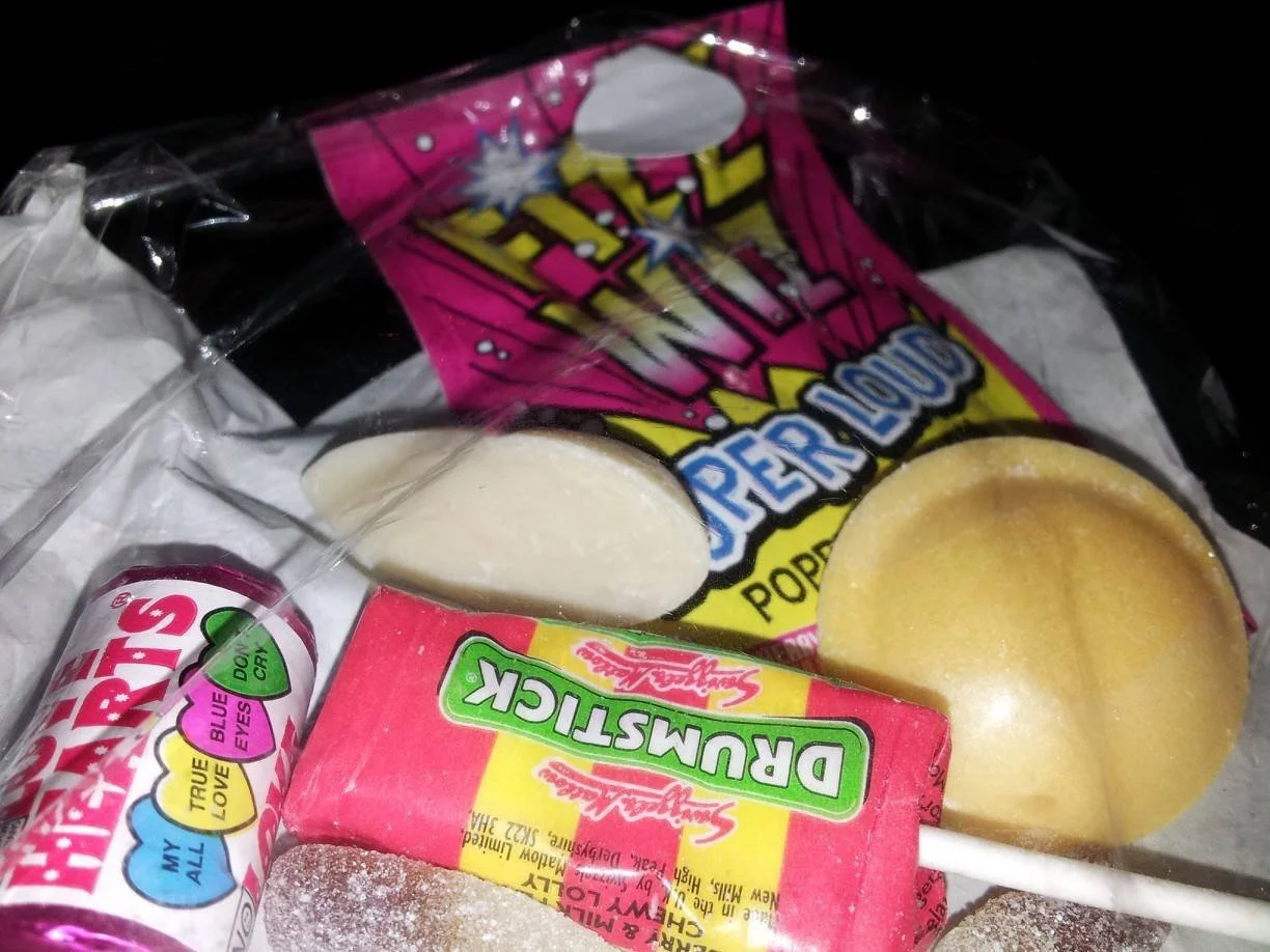 Selection of sweets from the 1980s including  Drumsticks, love hearts, flying saucers, Bubble gum, and lollipops with colourful packaging.