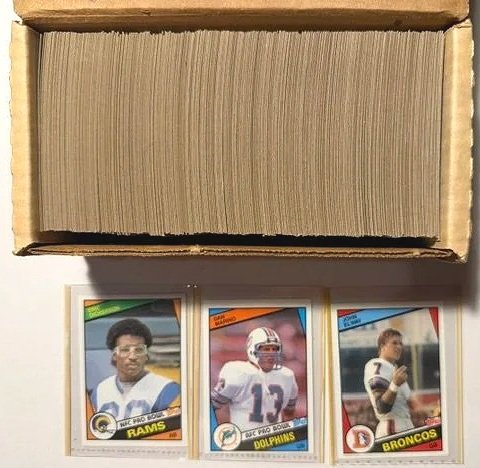 Box of football trading cards with three cards visible featuring players from the Los Angeles Rams, Miami Dolphins, and Denver Broncos.
