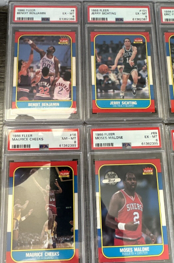 Four 1986 Fleer basketball trading cards featuring Benajmin Benoit, Jerry Sichting, Maurice Cheeks, and Moses Malone, all encased in protective plastic slabs.