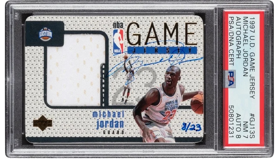 Michael Jordan NBA game-worn jersey autograph card from 1997 U.S. basketball series, with a photograph of him playing basketball, autographed and numbered 8 out of 23.