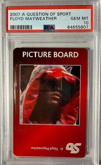 A graded trading card of Floyd Mayweather in a protective case. Label at the top indicates it is a 2007 'A Question of Sport' card, graded GEM MT 10 by PSA. The card features a close-up image of Floyd Mayweather in a red hooded outfit.
