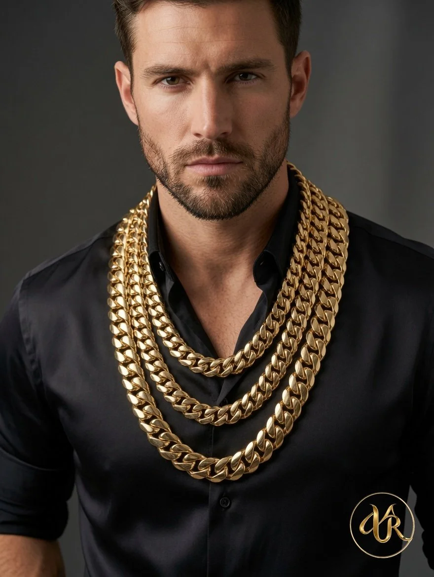 A man with a well-groomed beard and short brown hair wearing a black shirt and multiple gold chains around his neck.