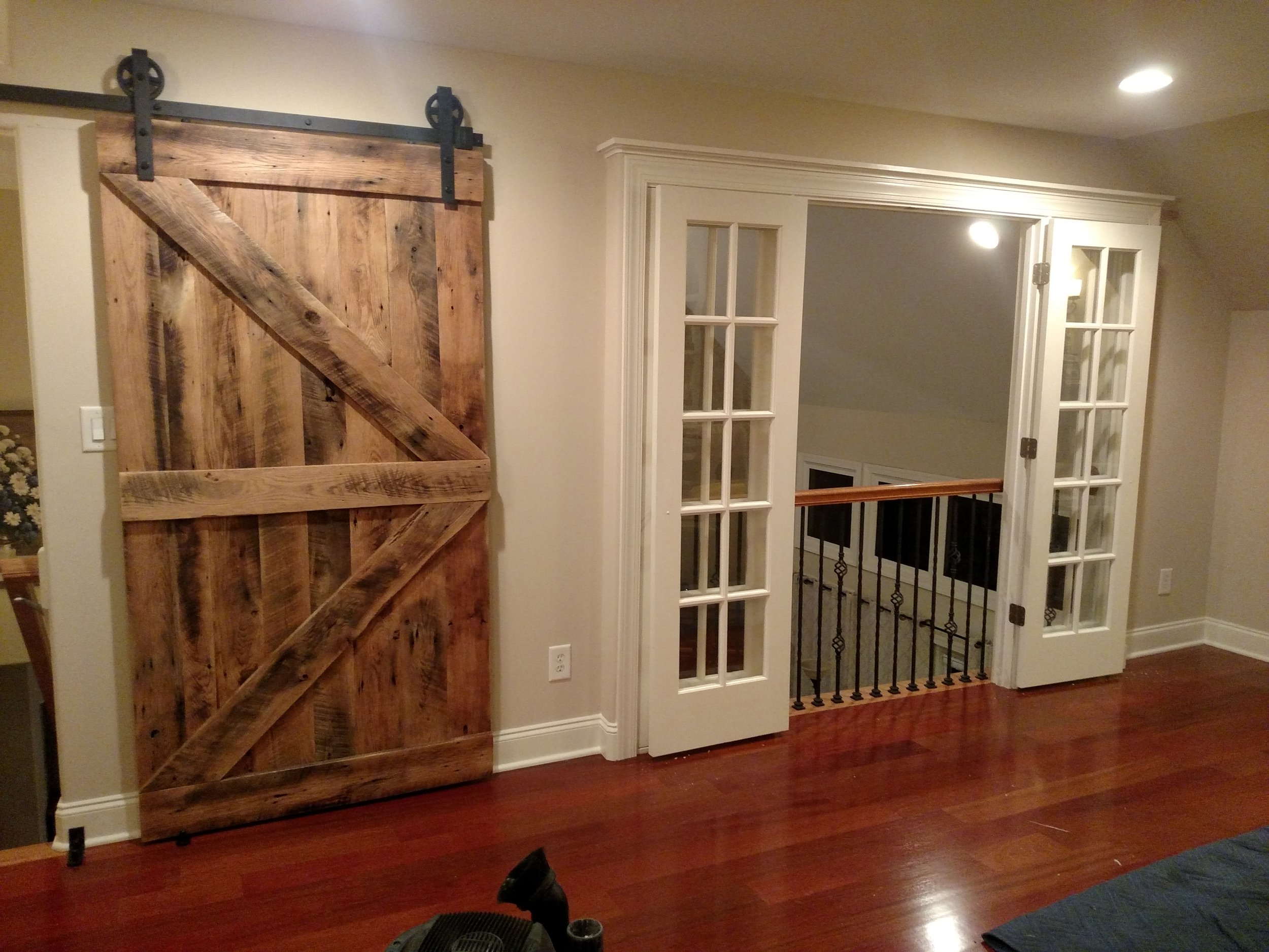 Custom 100+ year old barn wood used to create a custom heavy barn door and French door build out to promote privacy between floors