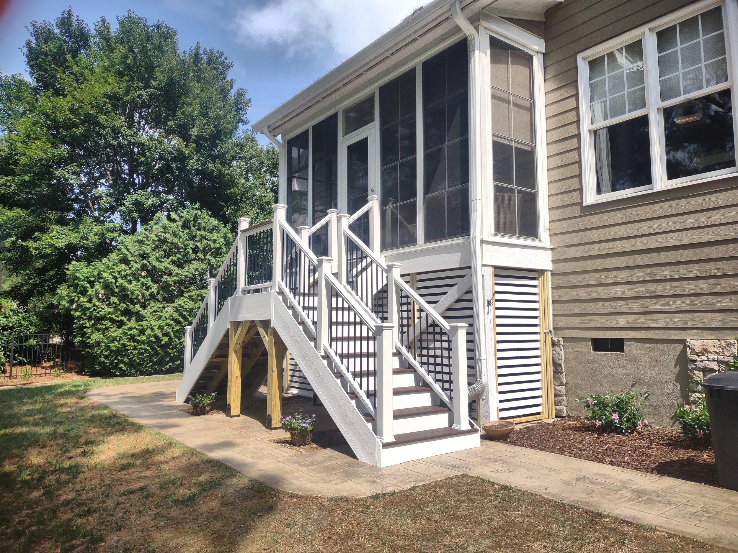 Premium dual staircase build with TimberTech treads and Trex railing. The decking and treads are fastened using TimberTech's hidden fastener system.. Below the sunroom there is a custom enclosed garden shed.
