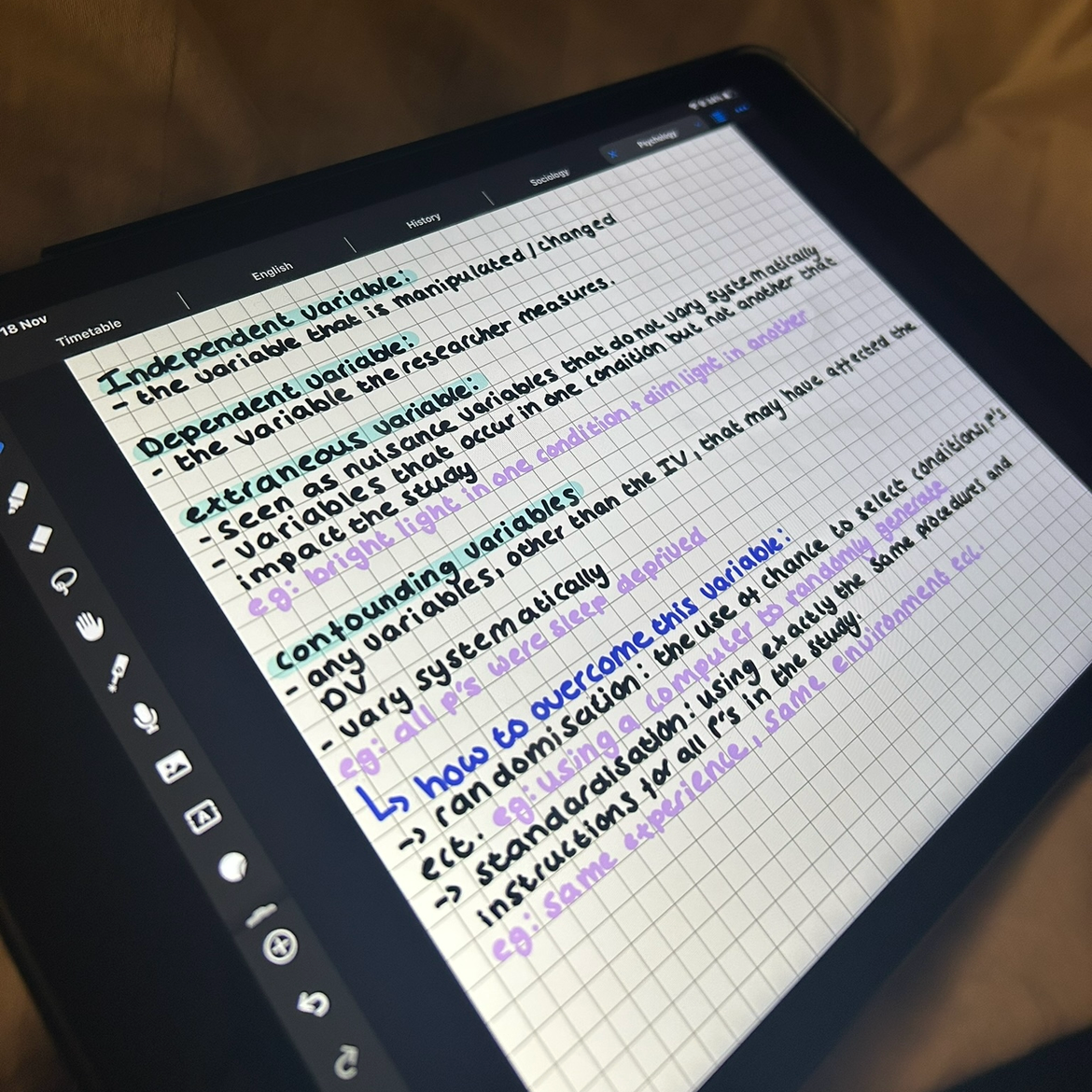 Digital tablet displaying handwritten notes on dependent and extraneous variables in research, with colored text and diagrams.