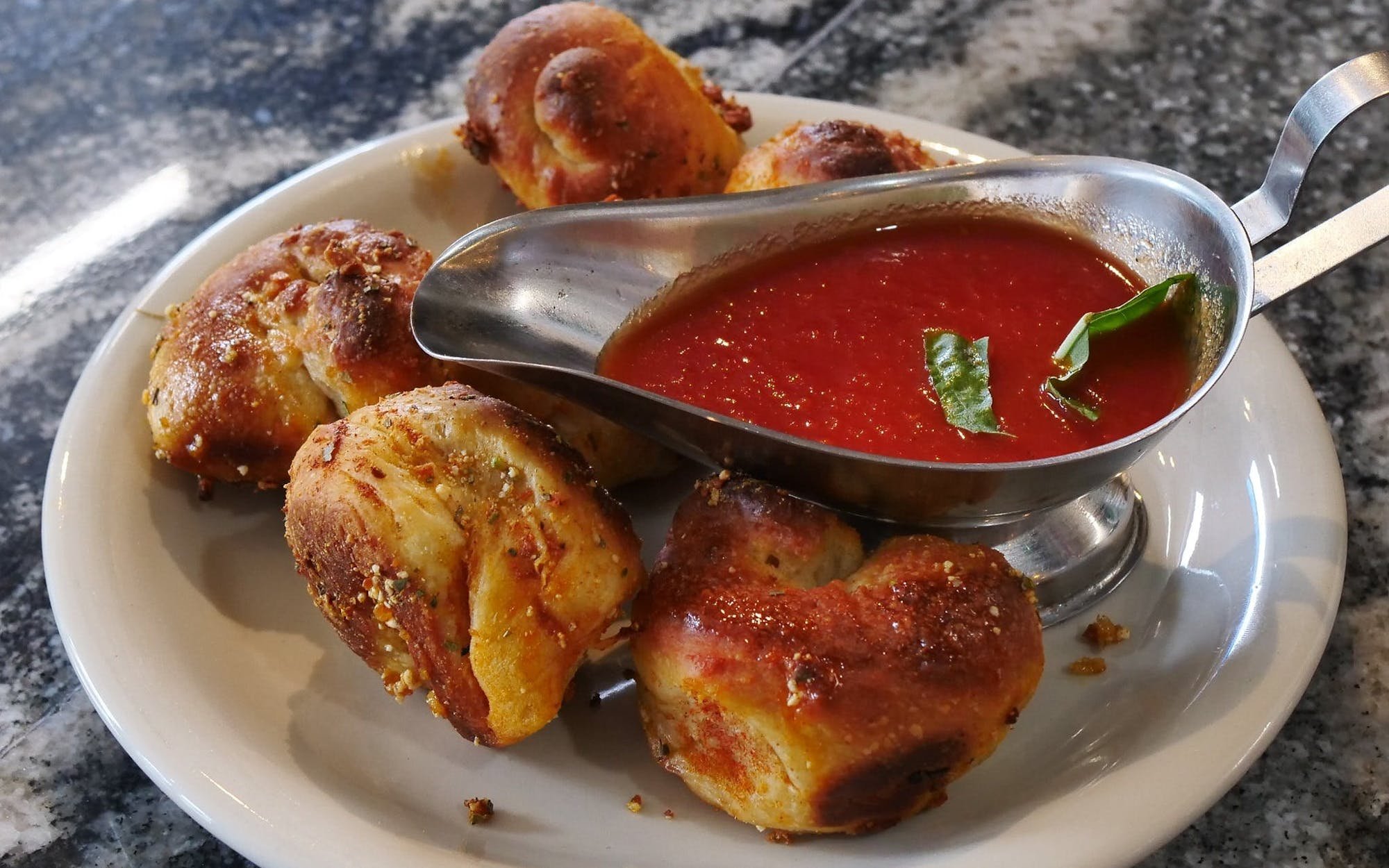 Plate of fried chicken pieces with spicy red dipping sauce garnished with green herbs.