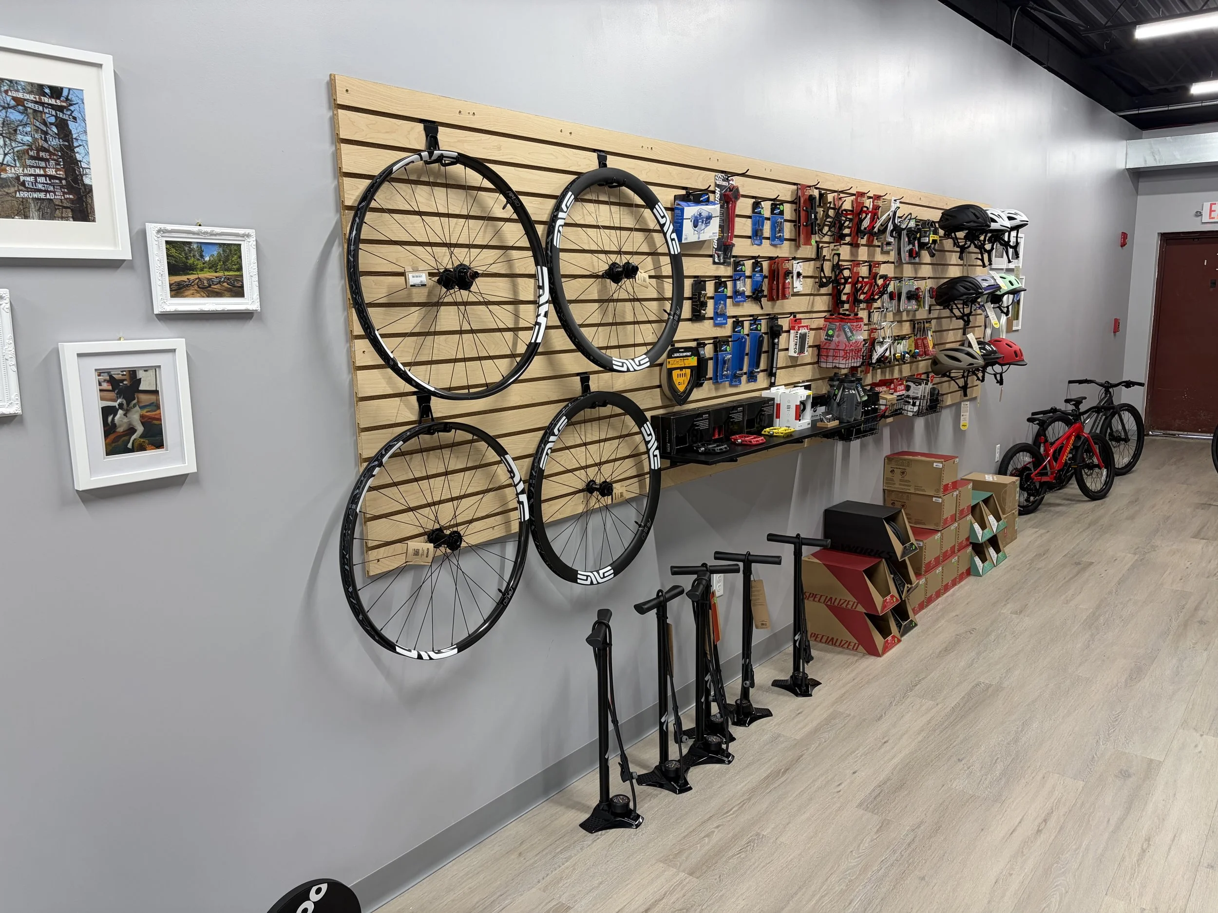 Bicycle shop interior displaying bike wheels, helmets, accessories, floor pumps, and bicycles