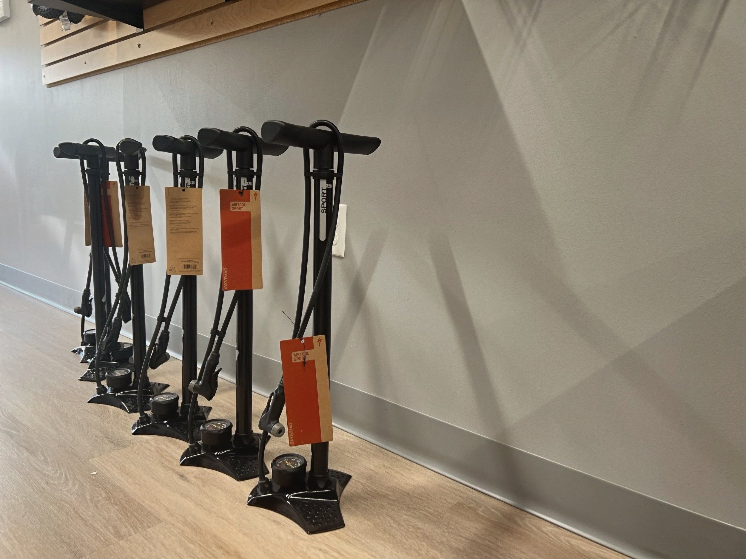 Black floor pumps with pressure gauges and bicycle-pump-style handles displayed in a sporting goods store