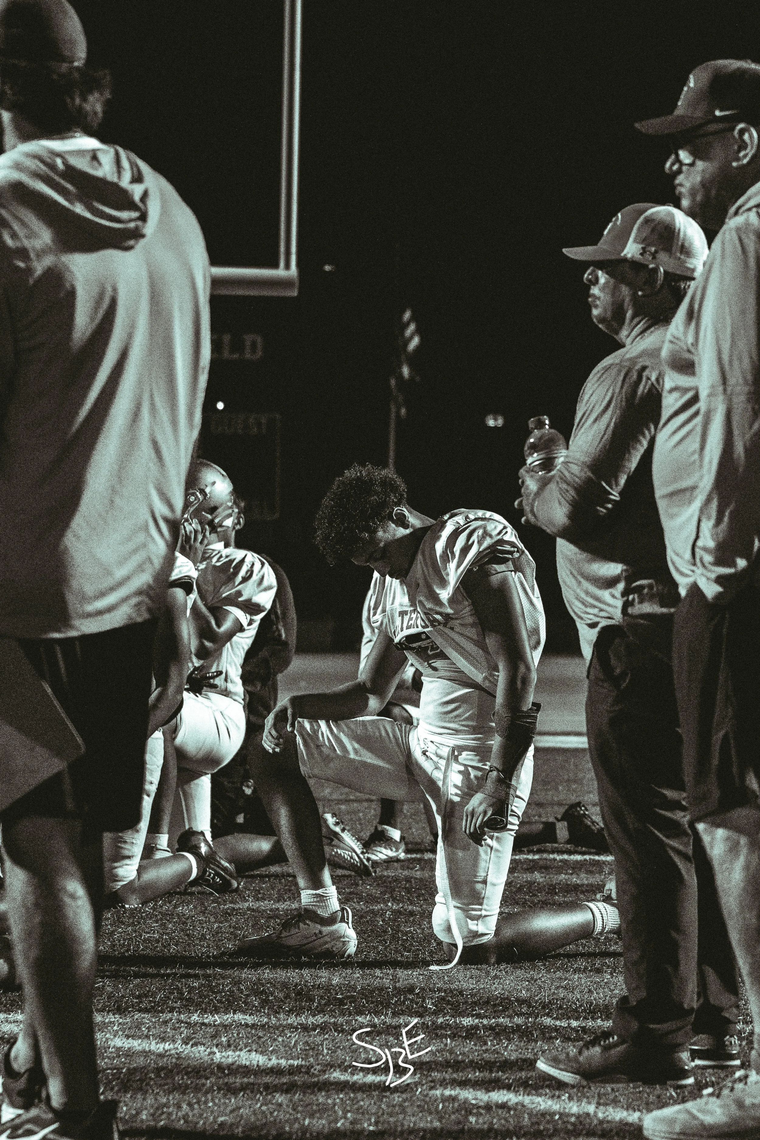 A football player showing emotion in the huddle of a team.