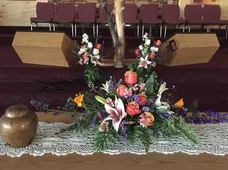 Religious altar with a crucifix, floral arrangements, and a decorative vase on a lace cloth.