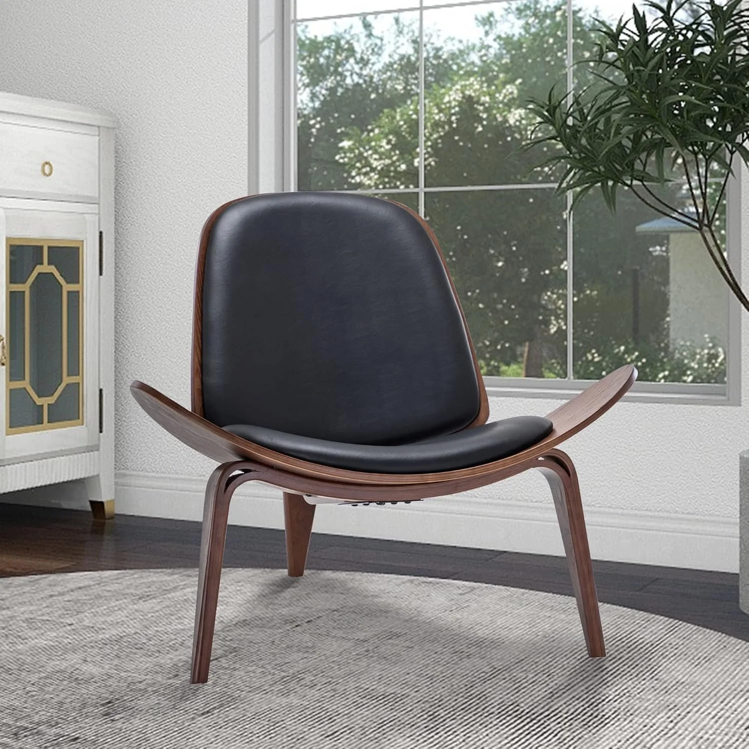 An MCM living room with a black leather and wood chair, a white cabinet, a large window with view of green trees, and a potted plant.