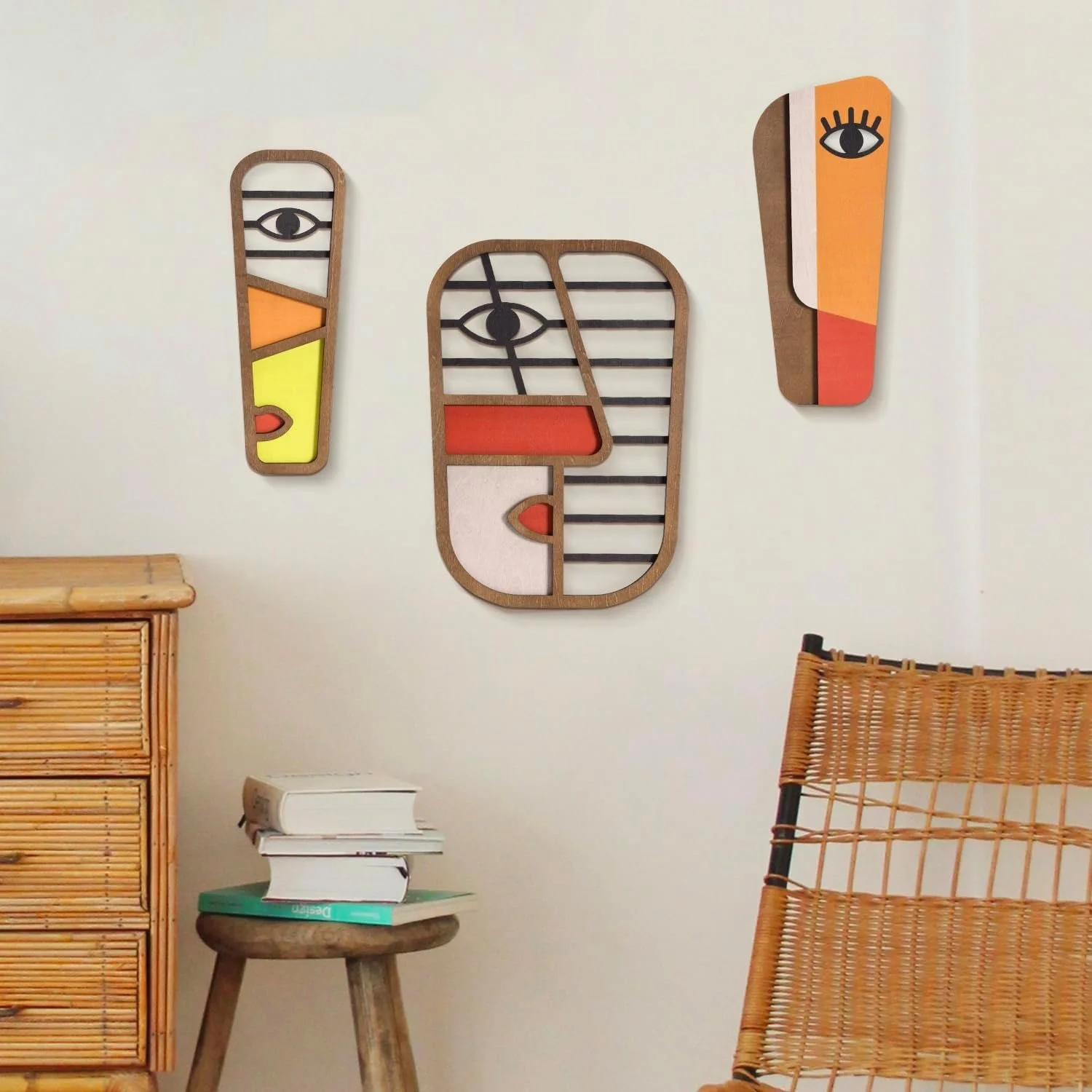 Decorative wall art with abstract faces and eyes in various colors hanging on a light-colored wall.