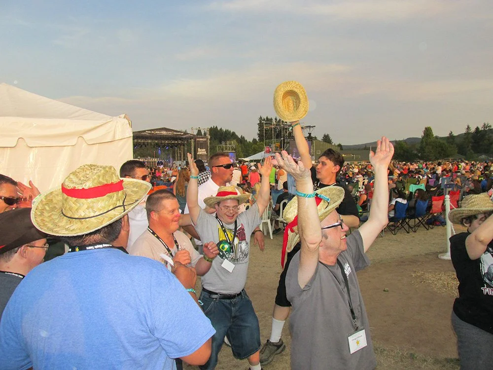 People wearing sombreros celebrating at an outdoor event with a stage in the background.