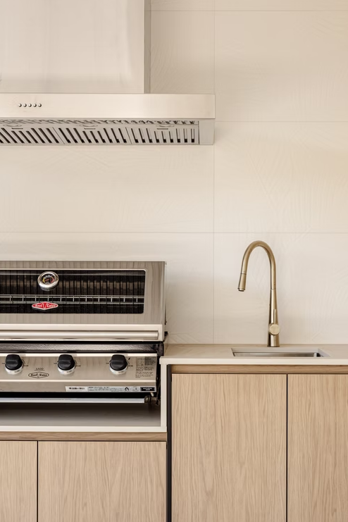 Kitchen with stove, range hood, and sink with a gold faucet