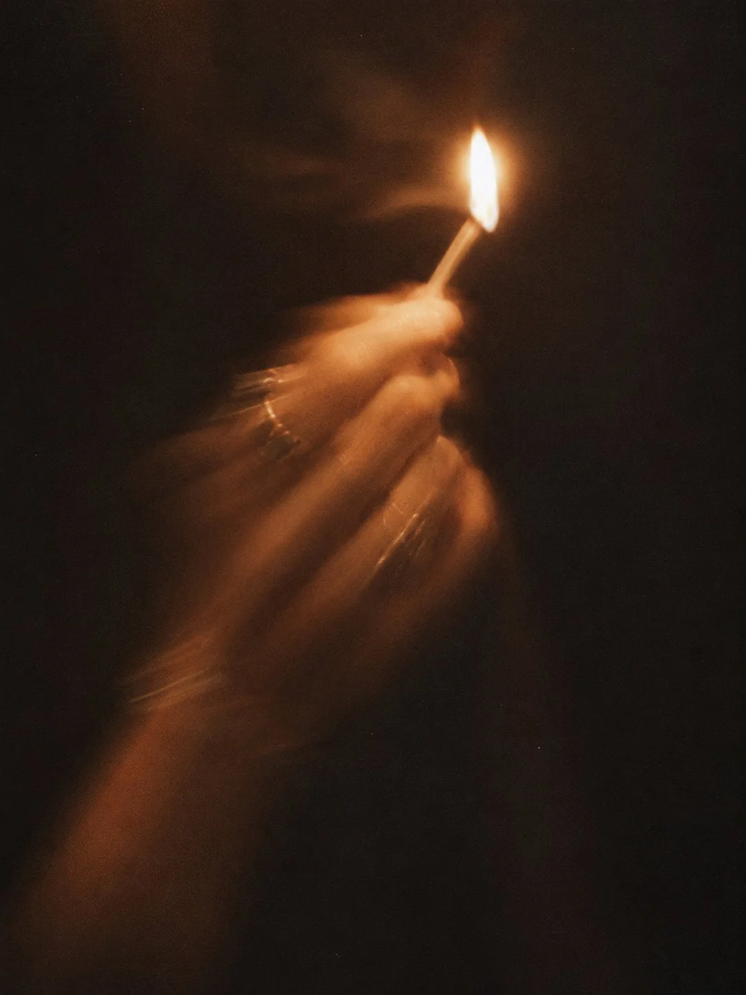 A hand holding a glowing match flame