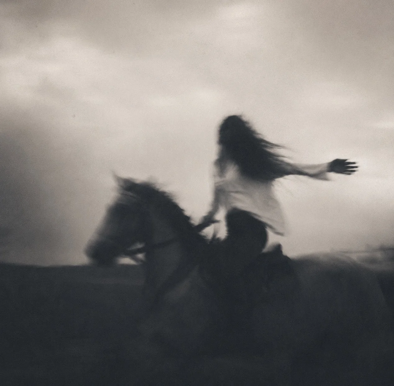 Black and white photo of a woman riding a horse
