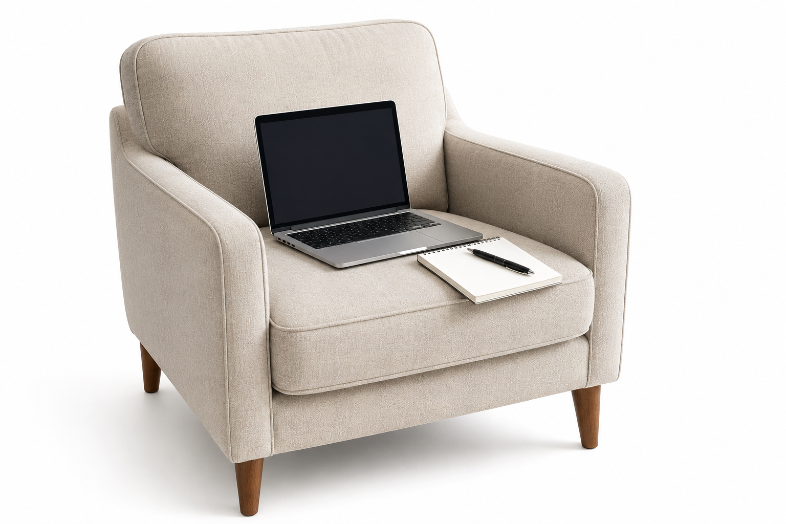 A beige armchair with wooden legs holding a laptop, a notepad, and a pen on its cushion.
