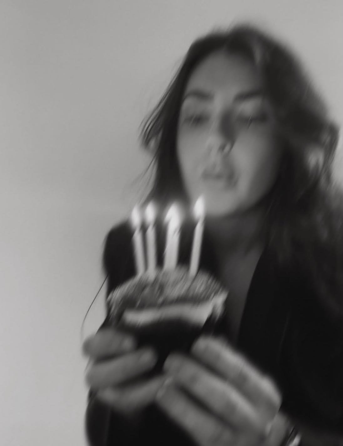 A woman with dark, wavy hair holding a fork with a burger, looking down at it.
