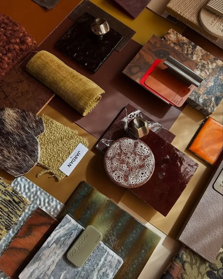 Collection of fabric samples, color swatches, and material samples in various textures and patterns displayed on a table.
