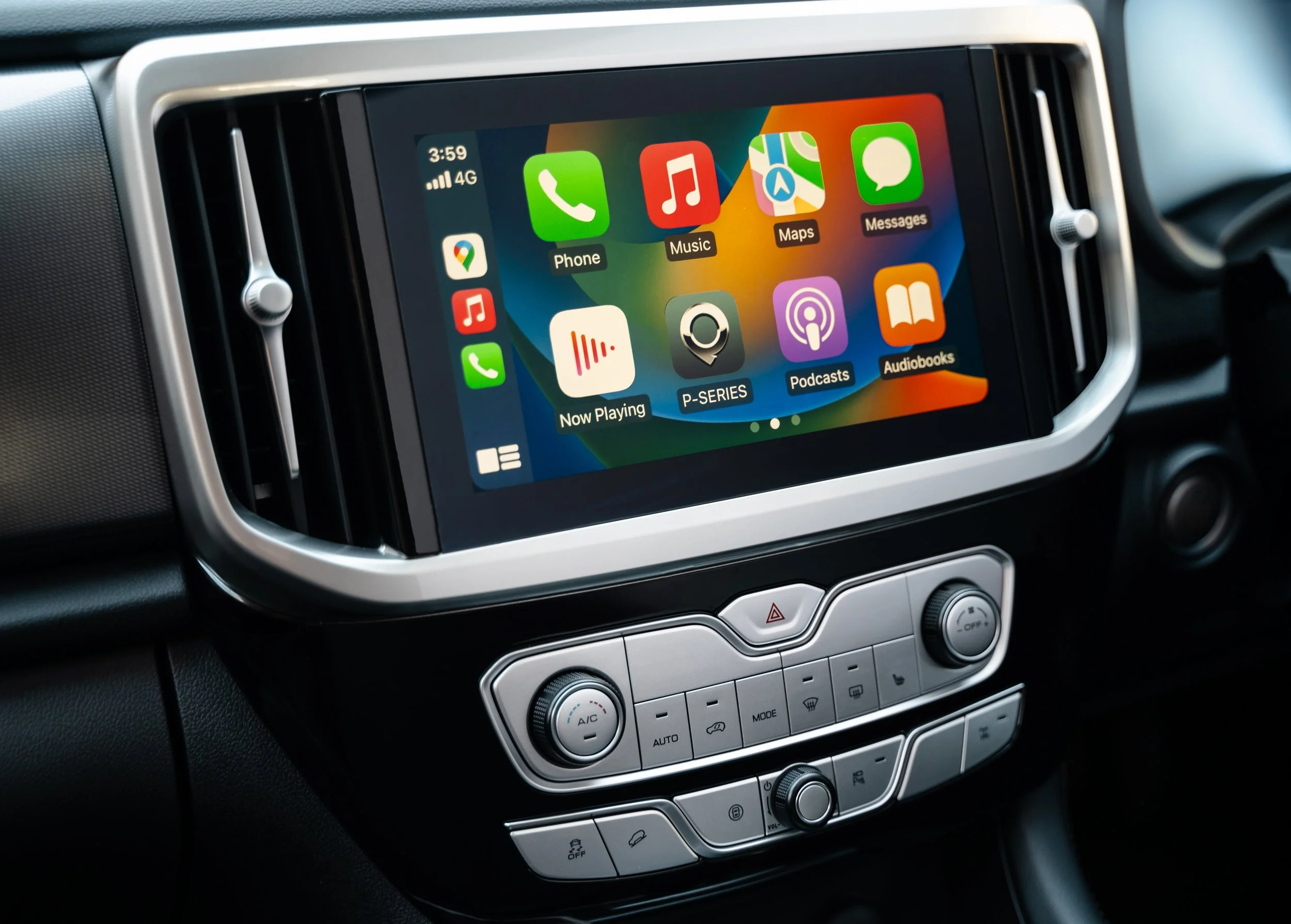 Car dashboard with a touchscreen displaying app icons for Phone, Music, Maps, Messages, Now Playing, P-Series, Podcasts, and Audiobooks, with climate control buttons below.