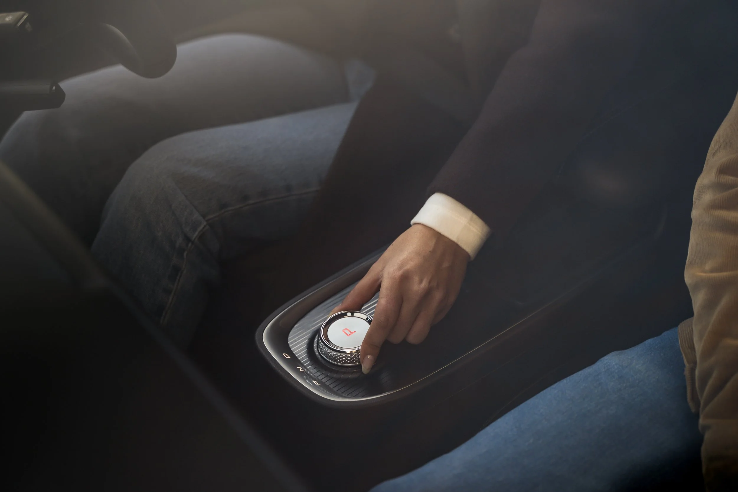 Person in casual clothing adjusting the gear selector in a modern car's center console.