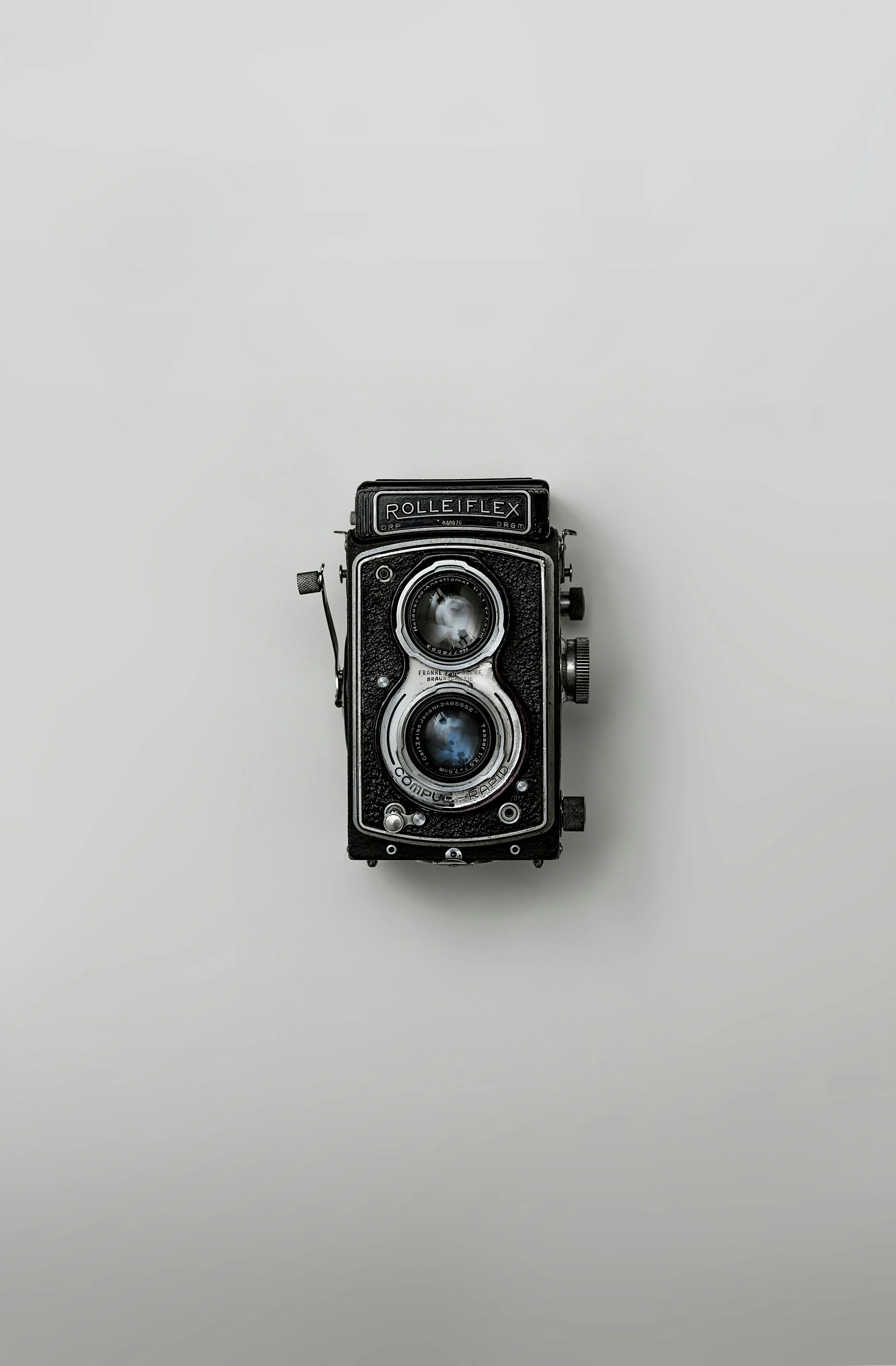 A vintage twin-lens reflex camera with black and silver body on a plain white background.