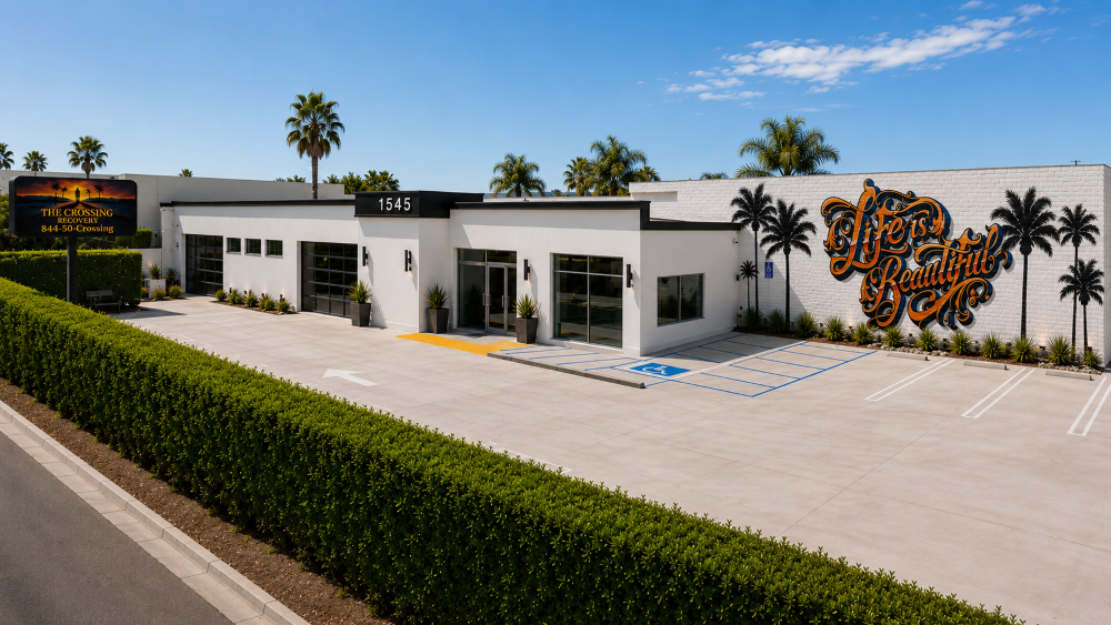 The Crossing Recovery drug and alcohol rehabilitation center in Costa Mesa, California, featuring a modern treatment facility, accessible parking, palm trees, and the “Life Is Beautiful” recovery mural.