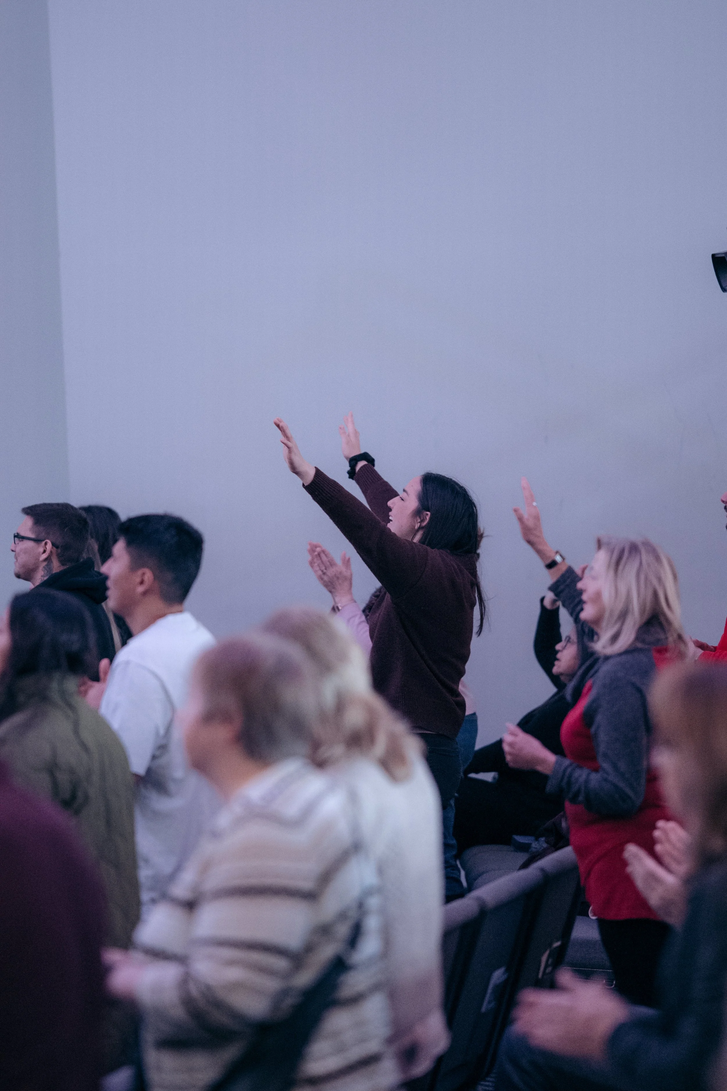 A group of people attending a presentation or conference, with some individuals raising their hands and clapping.