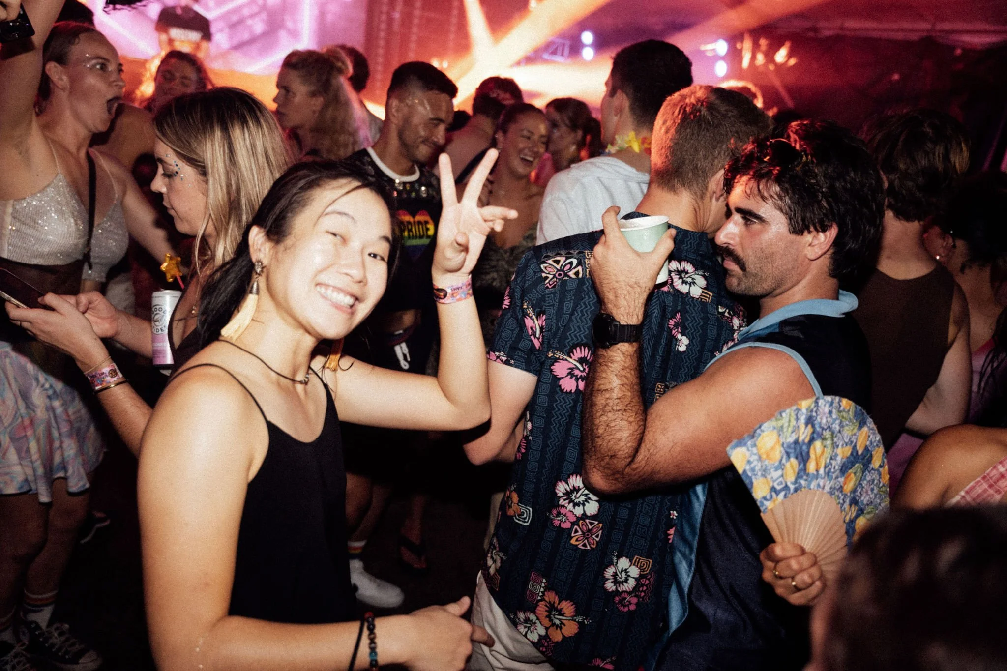 A group of young people dancing and enjoying themselves at a lively party or nightclub, with colorful lighting and a festive atmosphere.
