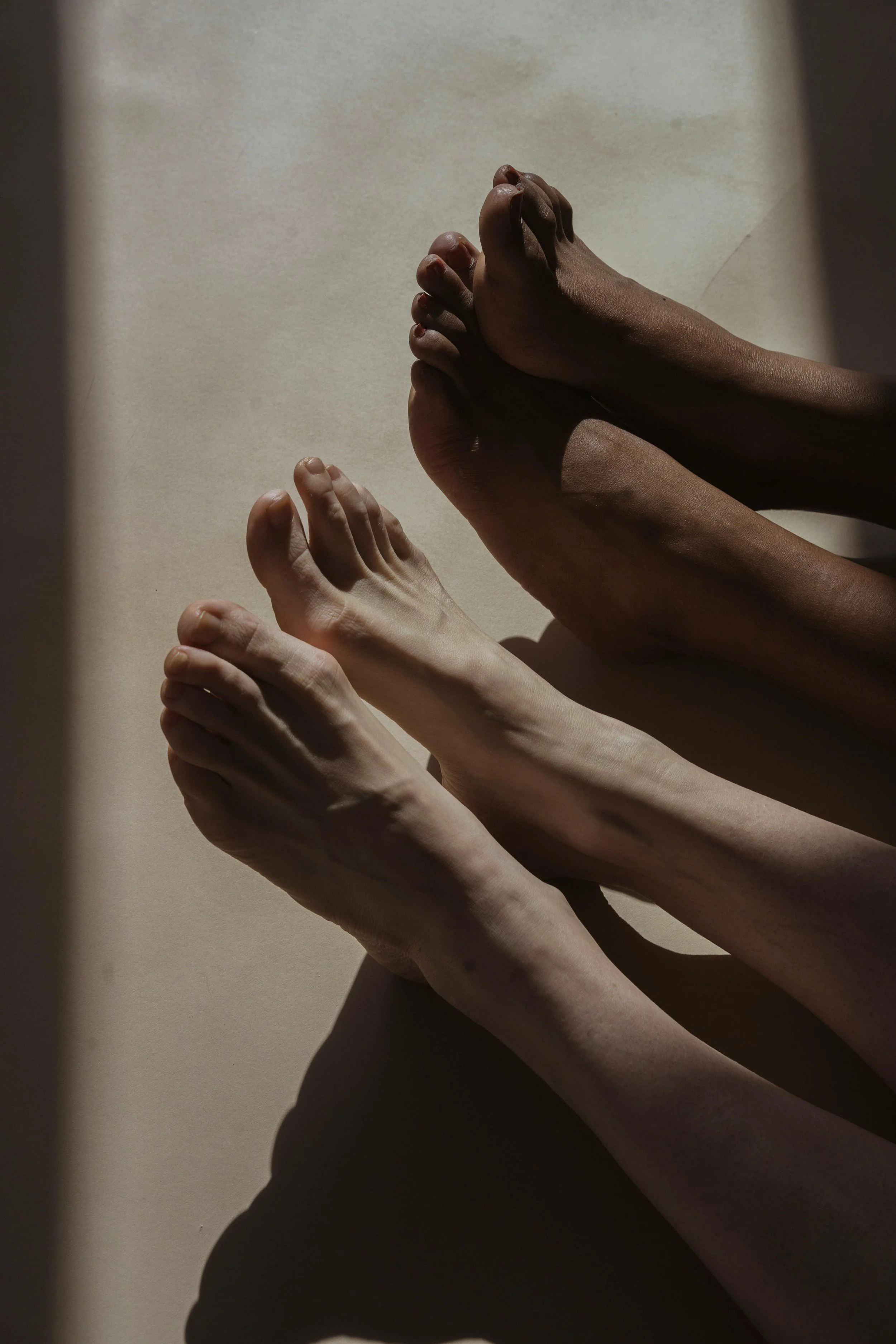 Six hands with different skin tones stacked and overlapping each other, casting shadows on a smooth surface.