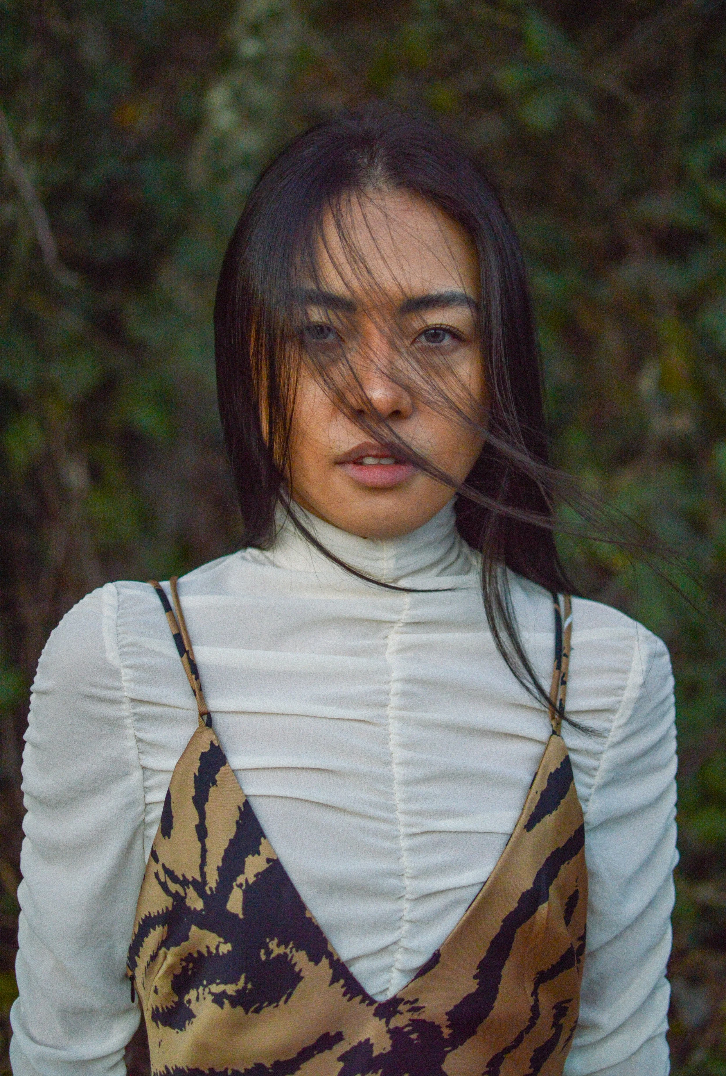 Editorial: Whispering WoodsA moody, natural-light editorial exploring the intersection of modern layered textures and raw outdoor environments. This portrait study utilizes soft, diffused lighting and organic movement to capture a minimalist autumn a