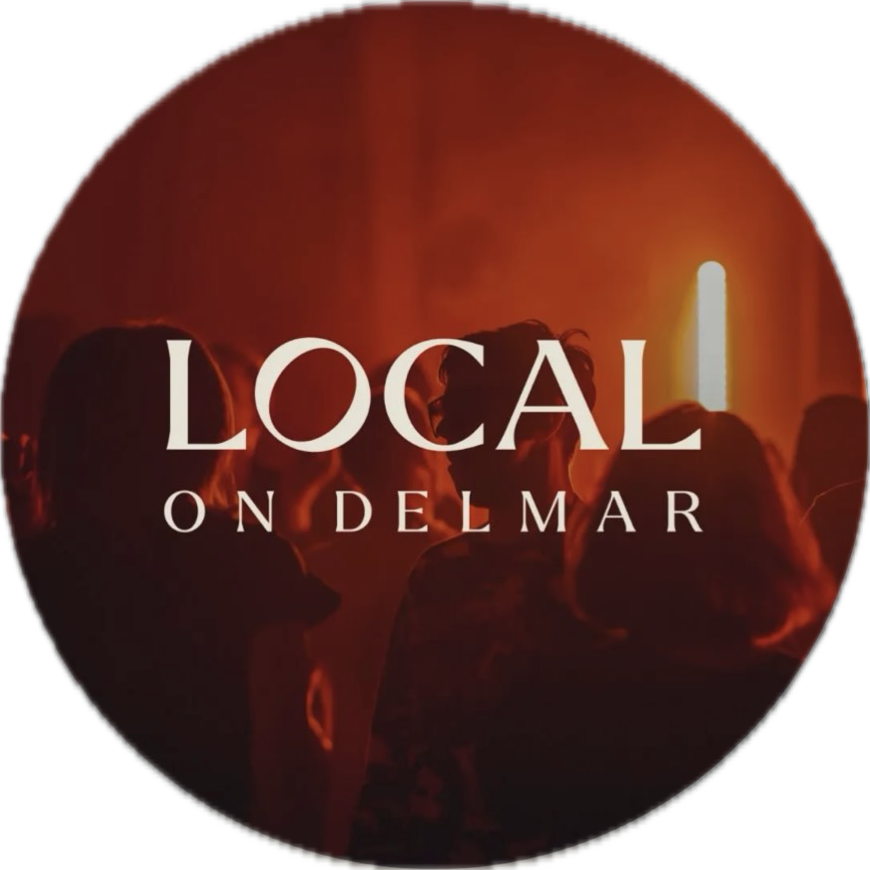 People socializing at an indoor event with warm lighting, with overlay text 'Local on Delmar'.