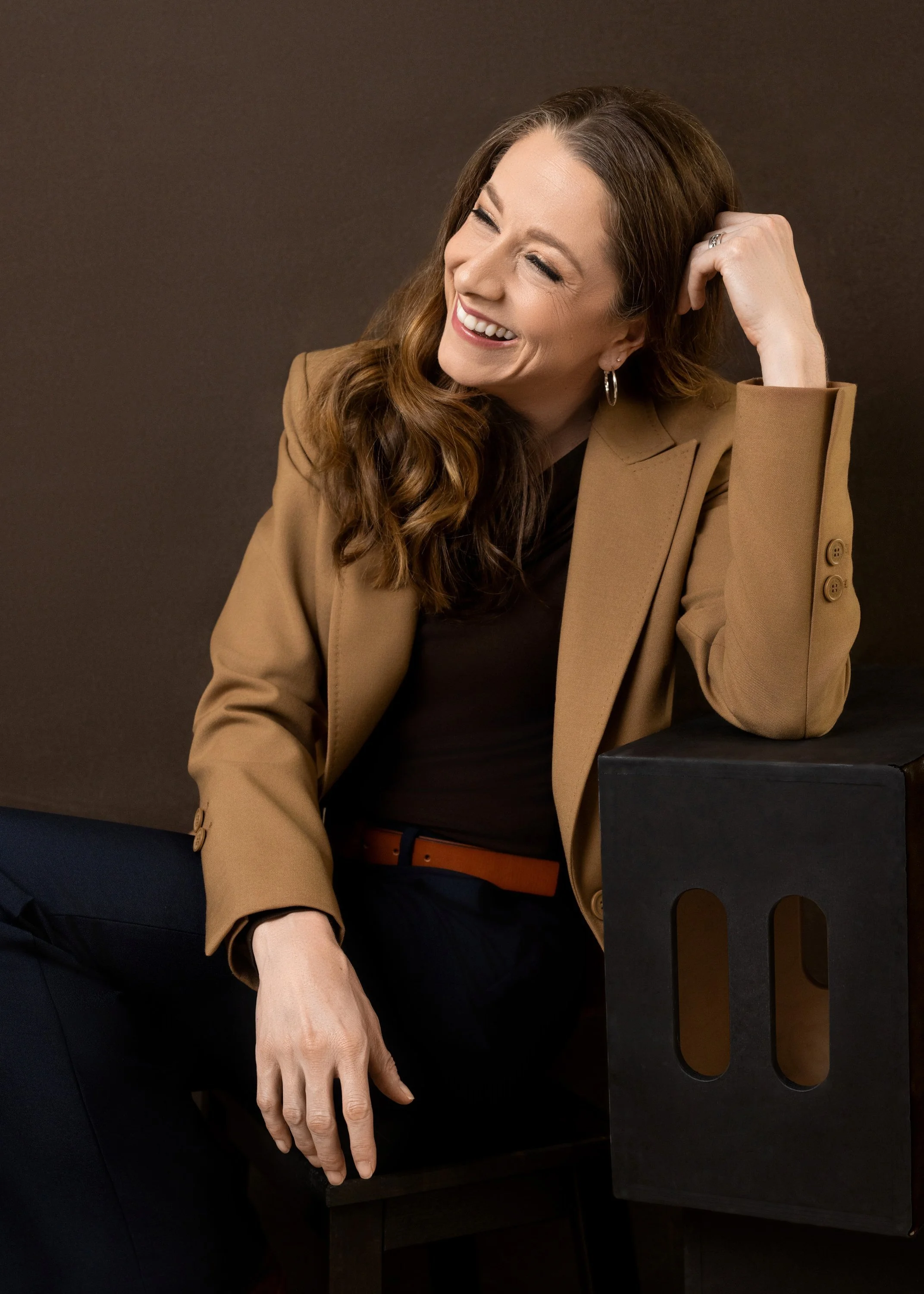 Seated professional portrait with a relaxed, candid expression.